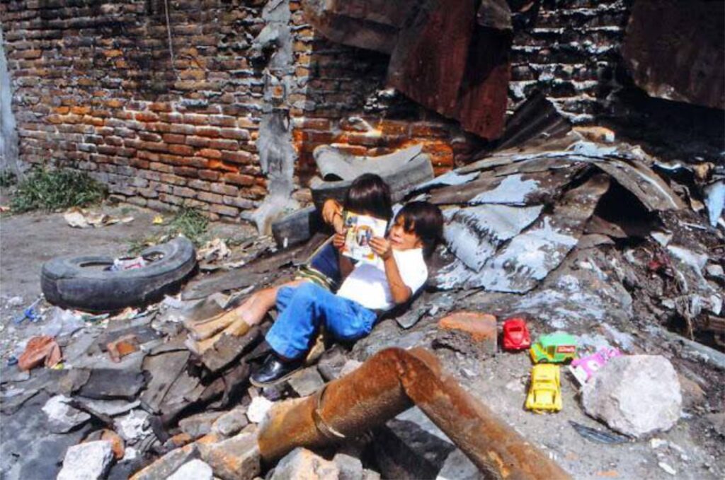 Children in an urban setting find solace in companionship and play, amidst a backdrop of worn infrastructure.