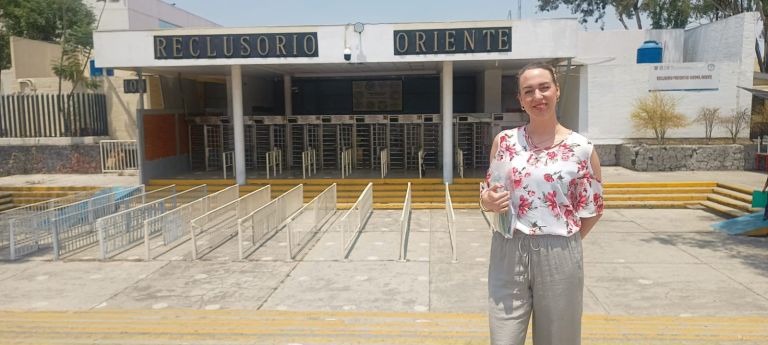 Mirjam stands smiling in front of the Reclusorio Oriente prison in Mexico City, conveying hope and determination for her prison ministry work.